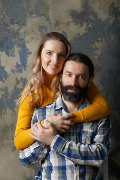 Conceito de amor e relacionamento. Casal adulto feliz se abraçando, sorrindo e olhando para a câmera, juntos em um fundo abstrato azul.