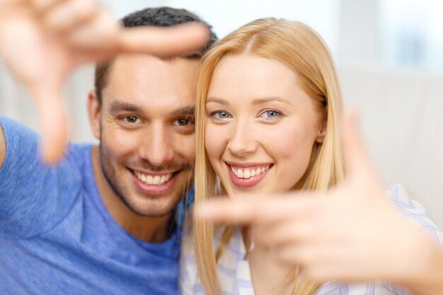 conceito de amor, família e felicidade - casal feliz sorridente fazendo gesto de quadro em casa