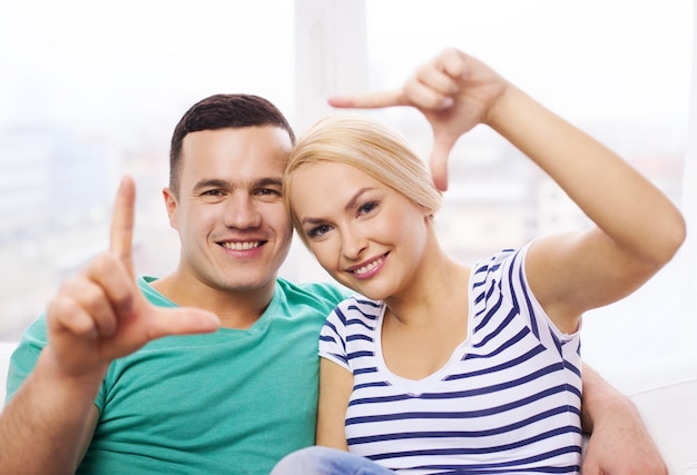 conceito de amor, família e felicidade - casal feliz sorridente fazendo gesto de quadro em casa