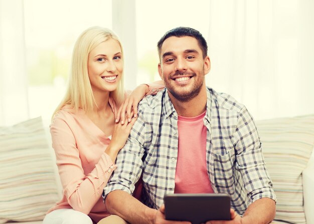 conceito de amor, família, tecnologia, internet e felicidade - casal feliz sorridente com computador tablet pc em casa