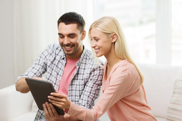 conceito de amor, família, tecnologia, internet e felicidade - casal feliz sorridente com computador tablet pc em casa