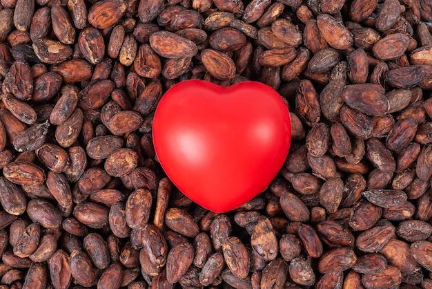 Foto conceito de amor para o dia dos namorados coração de borracha vermelha colocado em muitos grãos de cacau