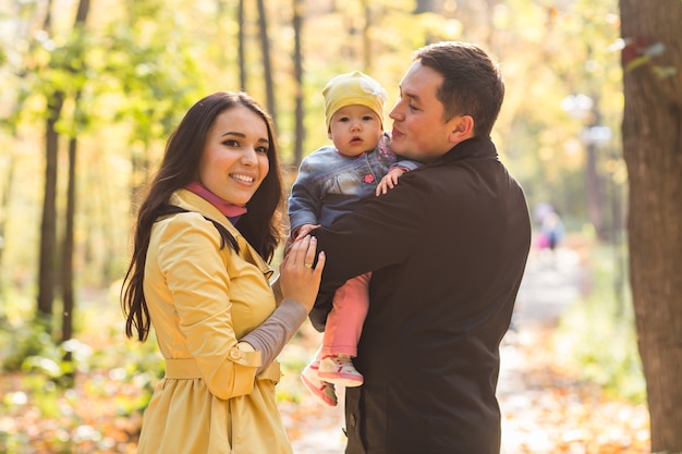 Conceito de amor, paternidade, família, estação e pessoas - casal sorridente com bebê no parque outono