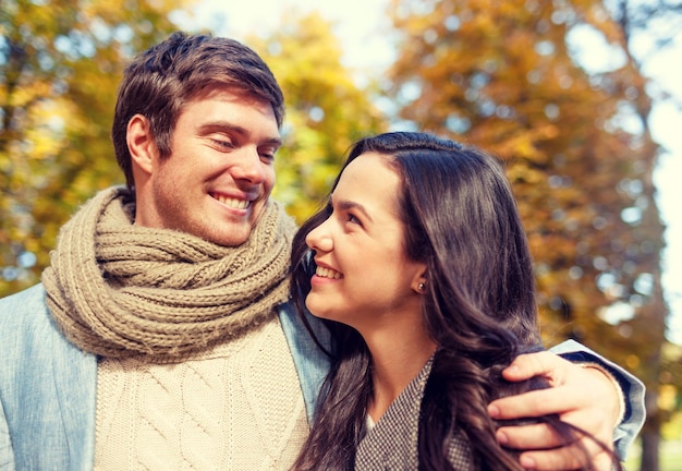 Conceito de amor, relacionamento, família e pessoas - casal sorridente abraçando no parque outono