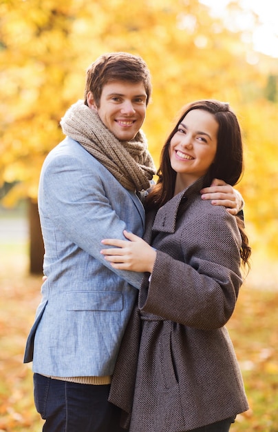 Conceito de amor, relacionamento, família e pessoas - casal sorridente abraçando no parque outono