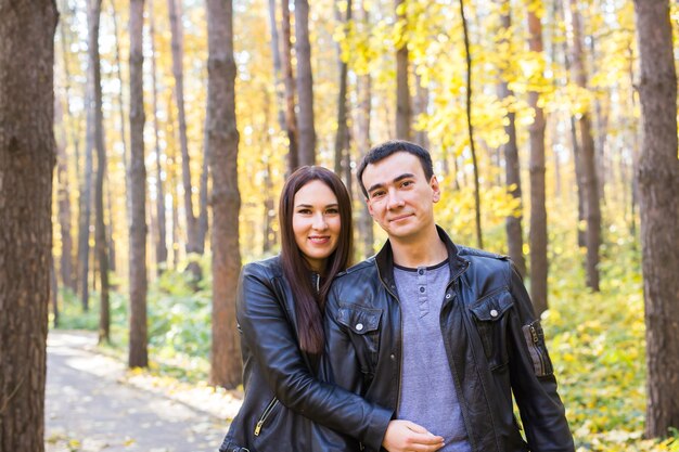 Conceito de amor, relacionamento, família e pessoas - casal sorridente, abraçando-se no parque outono.