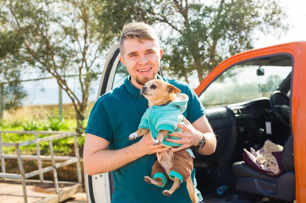 Conceito de animal de estimação, animal doméstico, estação e pessoas - Retrato de um homem feliz com seu cachorro caminhando ao ar livre