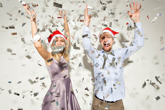 Conceito de ano novo, natal e festa - jovens alegres tomaram banho de confete em um fundo branco