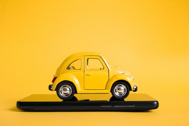 Conceito de aplicativo on-line móvel de táxi urbano. modelo de carro de táxi amarelo de brinquedo. mão segurando o telefone inteligente com aplicativo de serviço de táxi em exposição.