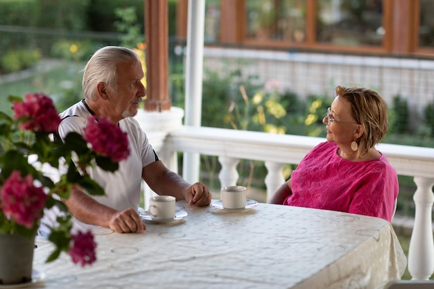 Conceito de aposentadoria Dois homens e mulheres sênior bebendo café e sorrindo ou discutindo planos futuros após a aposentadoria Casal maduro tomando café na varanda