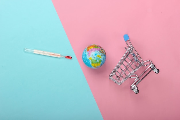 Conceito de aquecimento global. carrinho de compras com termômetro e globo em fundo pastel rosa-azulado. vista de cima, minimalismo