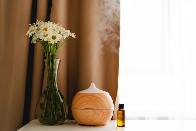 Foto conceito de aromaterapia difusor de óleo de aroma na mesa contra a janela