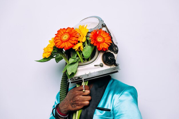 Conceito de arte com homem usando um capacete espacial e composição de flores