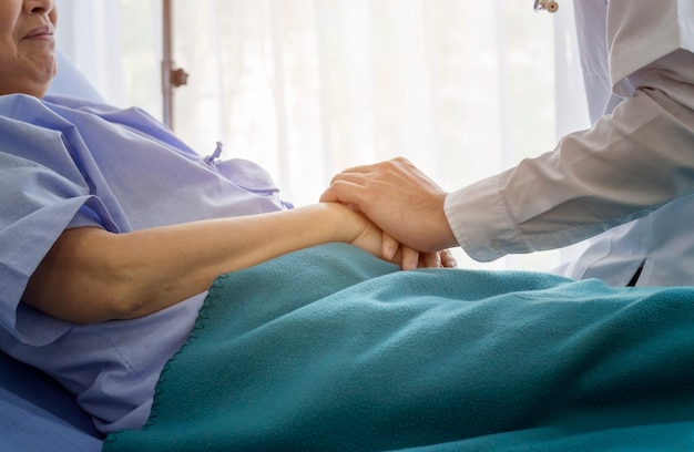 Conceito de atendimento ao paciente idoso; o doutor asiático está tomando a mulher paciente idosa no hospital.