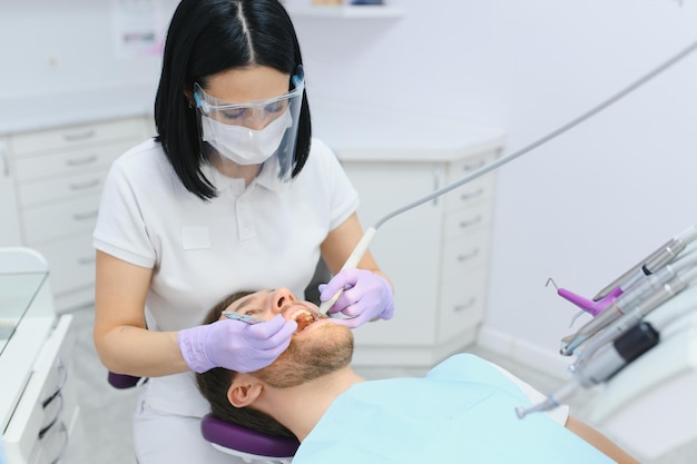 Conceito de atendimento odontológico Cara jovem e bonito no consultório do dentista