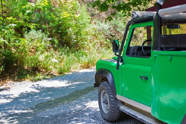 Conceito de atividade de viagens e verão - carro de safári verde na floresta