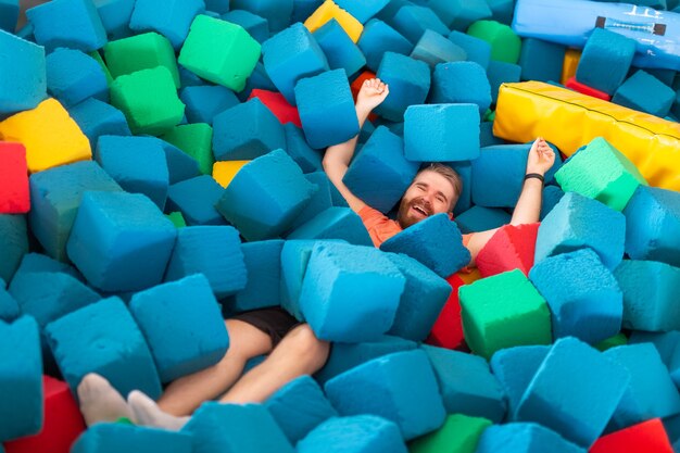 Conceito de atividade física, diversão, lazer e esporte - Homem engraçado e feliz se divertindo em uma cama elástica dentro de casa