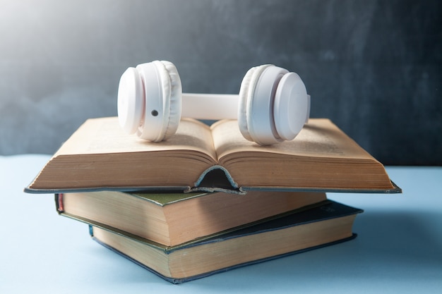 Foto conceito de audiolivro. livros e fones de ouvido na mesa