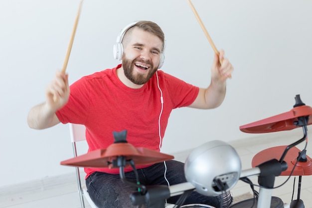 Conceito de baterista, hobbies e música - jovem baterista de camisa vermelha tocando bateria eletrônica.