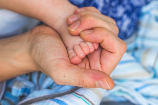 Conceito de bebê e recém-nascido Mãos da mãe segurando os pés do bebê recém-nascido