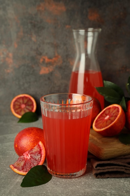 Conceito de bebida fresca com suco de laranja vermelho na mesa texturizada cinza