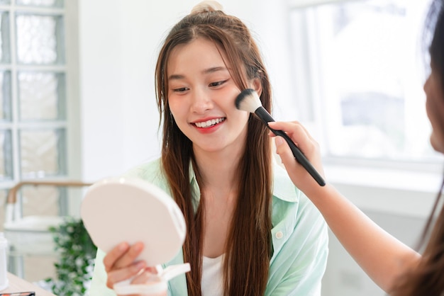 Conceito de beleza e cosmético Maquiador usando pincel com blush na bochecha e maquiagem do modelo