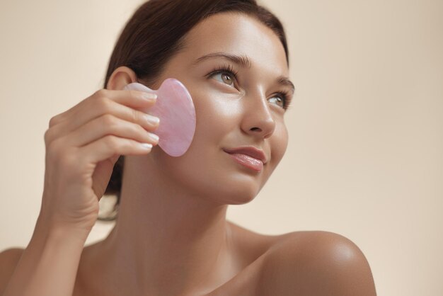 Conceito de beleza e cuidados com a pele da mulher com a ferramenta Gua Sha para massagem facial