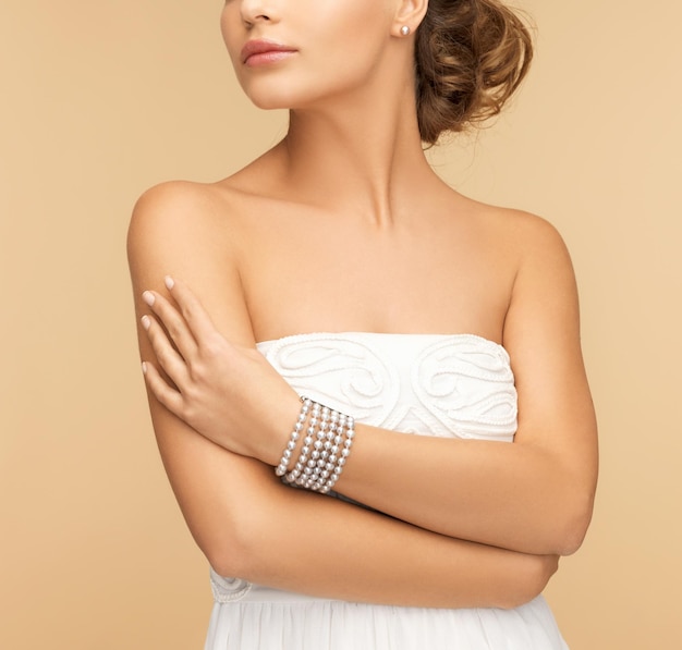 conceito de beleza e joias - linda mulher com brincos de pérola e pulseira