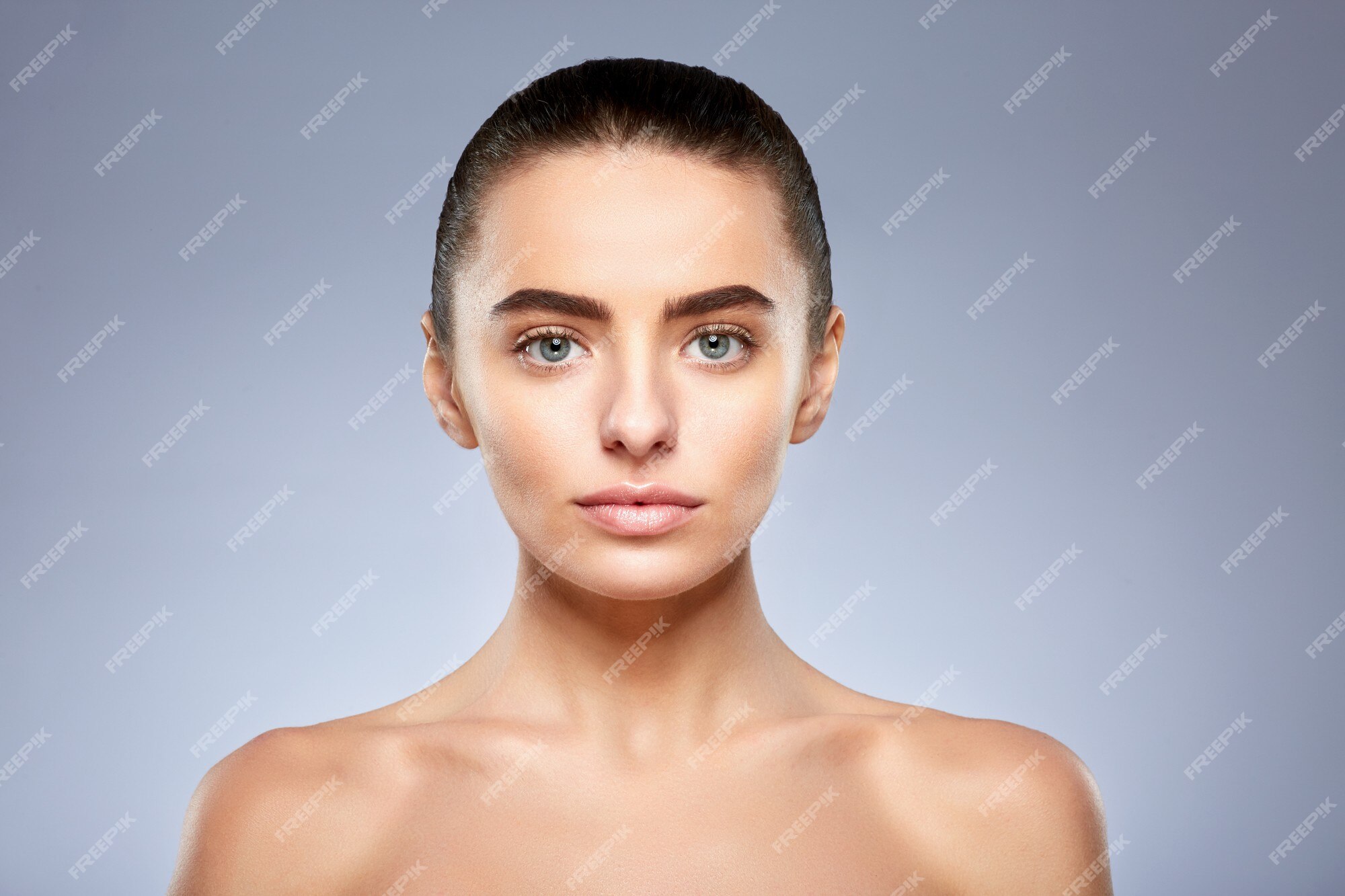 Beleza. close-up de menina bonita e natural com sorriso branco e ombros nus  rindo, sorrindo despreocupado. mulher jovem sem maquiagem mostrando efeito  após cosméticos, parede branca