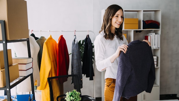 Conceito de blogueiro de moda Mulheres jovens que vendem roupas em streaming de vídeo PME de pequenas empresas iniciantes usando smartphone ou tablet recebendo e verificando no estúdio