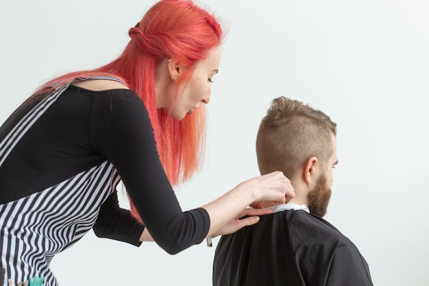 Conceito de cabeleireiro, cabeleireiro e barbearia - cabeleireiro de mulher cortando um homem barbudo.