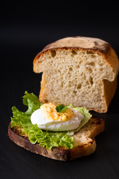 Conceito de café da manhã de alimentos orgânicos caseiro Ovo escalfado ou ovos Bento no pão de fermento torrado na placa de ardósia preta