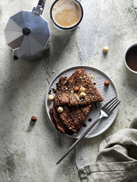 Conceito de café da manhã Panquecas de chocolate com nozes e molho em uma vista superior de fundo texturizado