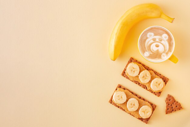 Conceito de café da manhã saudável com café com leite e pão crocante com manteiga de amendoim no amarelo