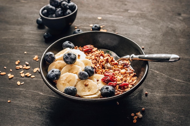 Conceito de café da manhã saudável com granola caseira mirtilos de banana e leite de aveia em fundo preto de madeira Foco seletivo