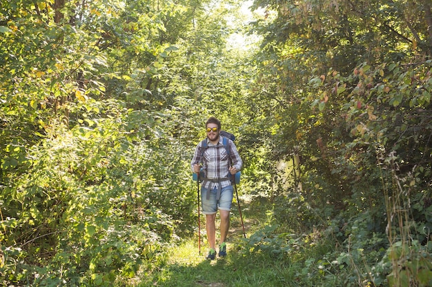 Conceito de caminhada, turismo e natureza - jovem viajante com mochila em pé sobre a floresta