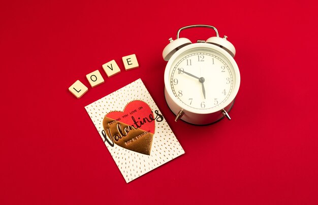 Conceito de cartão de dia dos namorados em vermelho, palavra de amor, letras, coração e despertador de manhã para casal, foto