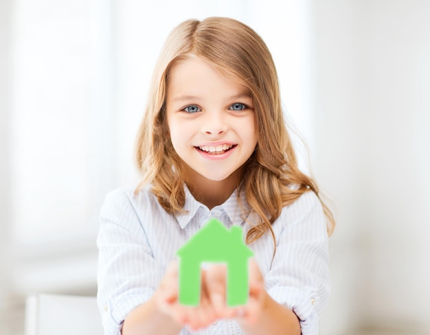 conceito de casa e família - menina segurando uma casa de papel verde