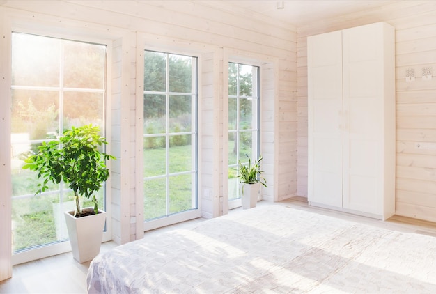 Conceito de casa e jardim Design de interiores de quarto brilhante e confortável em estilo escandinavo em casa de madeira branca com uma grande janela com vista para o pátio de verão