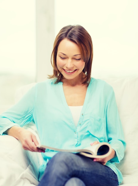 conceito de casa e lazer - mulher sorridente lendo revista em casa