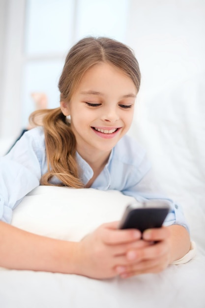 conceito de casa, lazer, tecnologia e internet - menina estudante com smartphone em casa