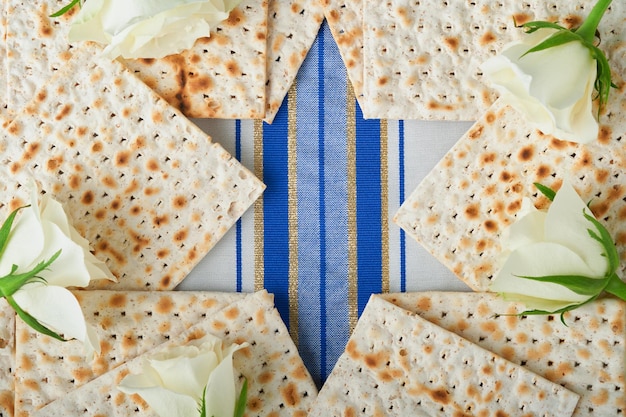 Conceito de celebração da Páscoa Azul Estrela de Davi feita de matzah rosas brancas e amarelas kipá e noz em fundo azul Ritual tradicional Comida judaica da Páscoa Pessach Feriado judaico Mock up