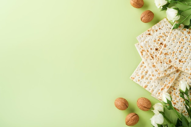 Conceito de celebração da páscoa Matzah vinho kosher vermelho noz e primavera lindas flores rosas Ritual tradicional pão judaico sobre fundo verde claro Comida de páscoa Pessach feriado judaico