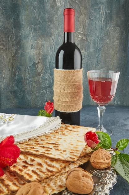 Conceito de celebração de Pessach feriado de Páscoa judaico Matzah no prato tradicional do Seder com garrafa de vinho tinto copo de vinho nozes e flores Copie o espaço para texto