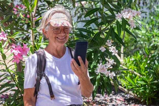 Conceito de chamada de vídeo mulher sênior sorridente sentada no parque usando telefone celular em bate-papo de vídeo