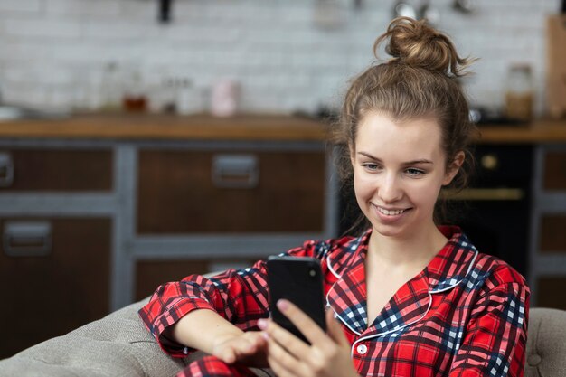Conceito de chat ou videochamada online. Linda adolescente feliz sentada no sofá se comunicando nas redes sociais
