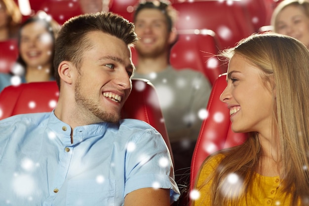 conceito de cinema, entretenimento e pessoas - amigos felizes ou casal assistindo filme e conversando no teatro com flocos de neve