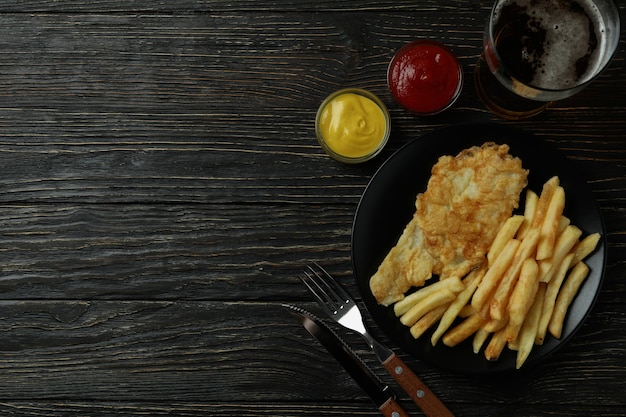 Conceito de comer saboroso com batatas fritas e peixe e cerveja na madeira