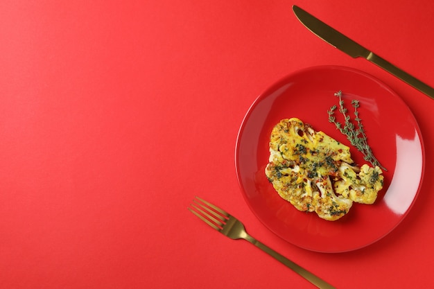 Conceito de comer saboroso com couve-flor assada no fundo vermelho.