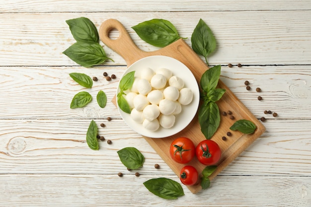 Conceito de comer saboroso com uma tigela de queijo mussarela no fundo branco de madeira